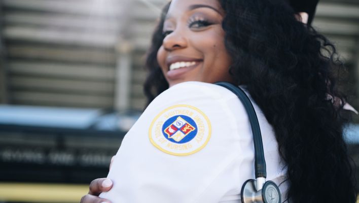 Black woman in medical uniform and stethoscope hanging over shoulder