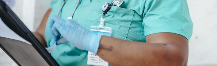 Crop African American woman in uniform standing in hospital and reading patient card while working